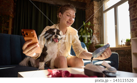 Young woman choosing retractable leash online with dog at home. Young woman choosing retractable leash online with dog at home. 143115520