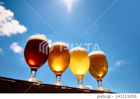 Four craft beer glasses on sunny wooden bar with blue sky. Four craft beer glasses on sunny wooden bar with blue sky. 143115850