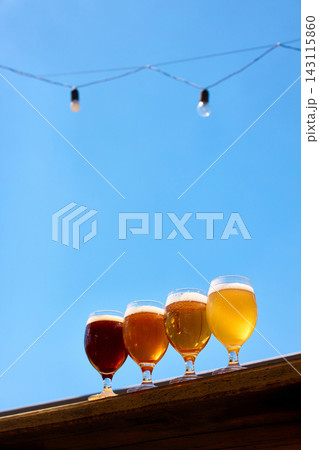 Craft beer glasses beneath string lights with large promotional copy space 143115860