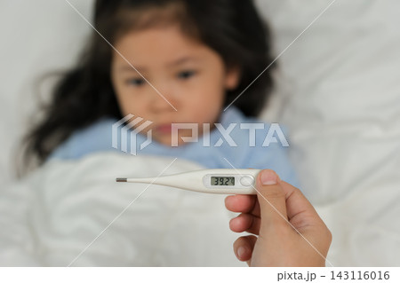 digital thermometer showing temperature of sick child with high fever in bed 143116016