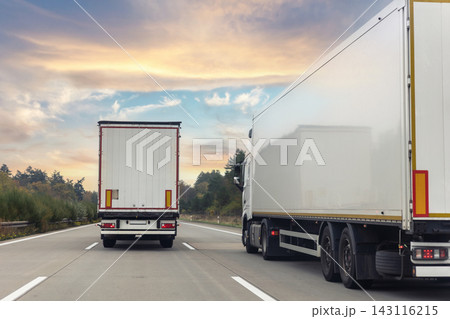Tail view white blank modern delivery big shipment cargo commercial semi trailer truck moving motorway road city urban suburb. Business distribution logistics service. Lorry driving highway sunset Tail view white blank modern delivery big shipment cargo commercial semi trailer truck moving motorway road city urban suburb. Business distribution logistics service. Lorry driving highway sunset 143116215