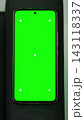 Isolated green screen chroma key artificial smartphone mockup display with tracking markers lying on a black fabric couch armrest. Static flat lay picture of phone template backdrop. Vertical shot. 143118337