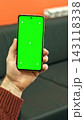 Male operator hand holding digital telephone device template with tracking crosses chroma key background. Close up of manager using smartphone green screen mockup inside dark workplace. Vertical shot. 143118338