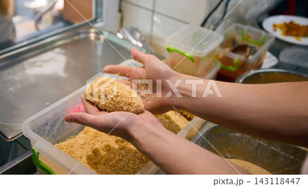 Cook forming breaded food portions by hand during kitchen prep 143118447