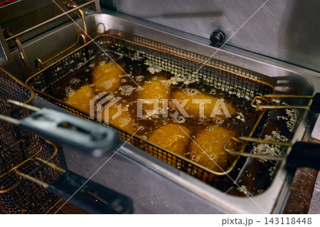 Batch of breaded portions deep frying in professional restaurant kitchen 143118448
