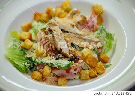 Fresh chicken salad with croutons and vegetables served on white restaurant plate 143118450