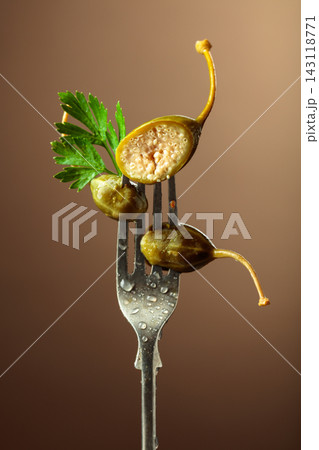 Canned capers with parsley leaves on a fork. 143118771