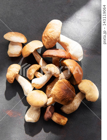Fresh porcini mushrooms on dark surface ready for cooking Fresh porcini mushrooms on dark surface ready for cooking 143119064