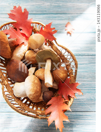 Wild mushrooms and autumn leaves in wicker basket 143119066