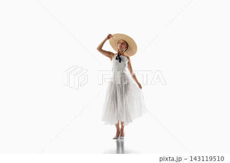 Stylish woman poses in airy white dress and wide brim summer hat Stylish woman poses in airy white dress and wide brim summer hat 143119510