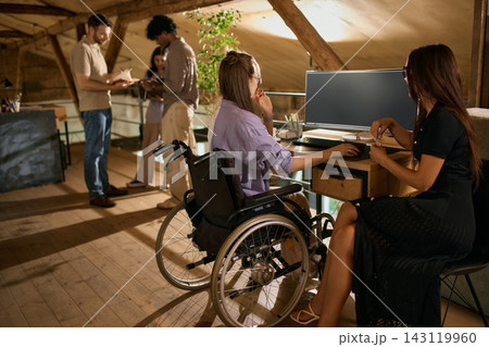 Two businesswomen collaborating at desktop computer in inclusive office Two businesswomen collaborating at desktop computer in inclusive office 143119960