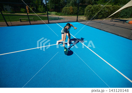 Male padel athlete in black sportswear moving dynamically across minimalist blue outdoor court Male padel athlete in black sportswear moving dynamically across minimalist blue outdoor court 143120148
