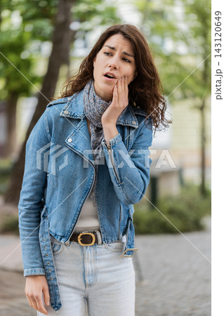 Young woman having toothache walking in city street touching cheek with painful dental issue in town Young woman having toothache walking in city street touching cheek with painful dental issue in town 143120649