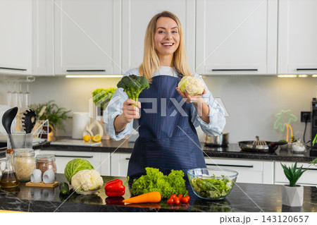 Young woman showing broccoli and cauliflower in kitchen promoting keto diet healthy grocery shopping 143120657