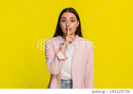 Woman placing finger on lips showing silence gesture asking for quiet serious thoughtful expression Woman placing finger on lips showing silence gesture asking for quiet serious thoughtful expression 143120730