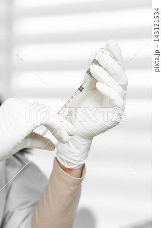A healthcare worker's gloved hands carefully draw medication into a syringe from a vial, emphasizing precision and safety. The background features a clean, modern medical setting A healthcare worker's gloved hands carefully draw medication into a syringe from a vial, emphasizing precision and safety. The background features a clean, modern medical setting 143121534