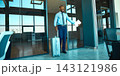 Excited male traveler holds documents beside a suitcase at airport doorway with joyful anticipation 143121986