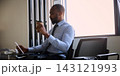 Business traveler reviews a tablet and drinks coffee in airport waiting area with calm concentration 143121993