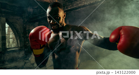 Confident fighter throws a powerful punch through gym smoke with competitive excitement Confident fighter throws a powerful punch through gym smoke with competitive excitement 143122000