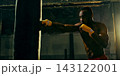 Skilled boxer lands a straight punch on a heavy bag with precise control 143122001