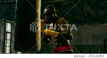 Dedicated fighter practices close-range punches on a heavy bag with relentless energy Dedicated fighter practices close-range punches on a heavy bag with relentless energy 143122003