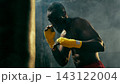 Concentrated combat athlete raises wrapped fists in a smoky gym with disciplined focus 143122004