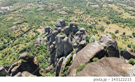 Horizontal aerial drone view of iconic towering sandstones monoliths and rock pillars rising above green forest valley in Meteora Kalambaka Greece Horizontal aerial drone view of iconic towering sandstones monoliths and rock pillars rising above green forest valley in Meteora Kalambaka Greece 143122215