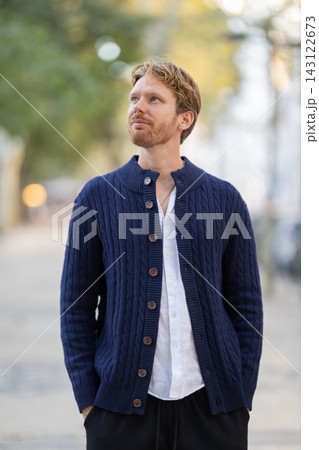 Man wearing a dark blue cardigan in a city setting during daytime Man wearing a dark blue cardigan in a city setting during daytime 143122673