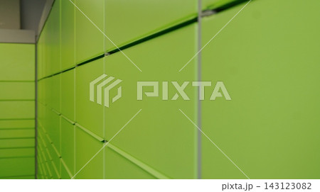 Close view of a long wall of bright green storage lockers with repeating doors and metal dividers. The image represents order, security, and efficient use of space in an automated storage system. Close view of a long wall of bright green storage lockers with repeating doors and metal dividers. The image represents order, security, and efficient use of space in an automated storage system. 143123082