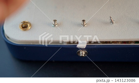 Several small metallic stud earrings are arranged inside the cream interior of an open blue jewelry case. The organized display represents order, protection, and careful storage of delicate personal 143123086