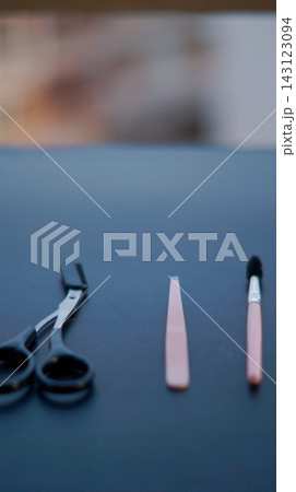 Black scissors, a slim pink grooming tool, and a small brush are arranged on a dark tabletop. Minimal grooming accessories symbolize personal care, precision, and everyday beauty routine. Black scissors, a slim pink grooming tool, and a small brush are arranged on a dark tabletop. Minimal grooming accessories symbolize personal care, precision, and everyday beauty routine. 143123094
