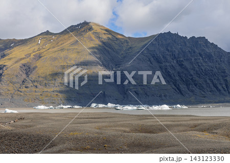 Floating icebergs on a glacial lake below rugged mountains near Skaftafellsjokull Floating icebergs on a glacial lake below rugged mountains near Skaftafellsjokull 143123330