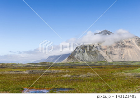 Cloud-covered Vestrahorn above grassy flats and pools at Stokksnes, Iceland Cloud-covered Vestrahorn above grassy flats and pools at Stokksnes, Iceland 143123485