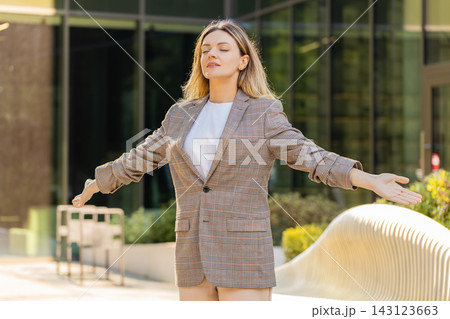 Young woman relaxing walking in city street taking deep breath during calm break near office center Young woman relaxing walking in city street taking deep breath during calm break near office center 143123663
