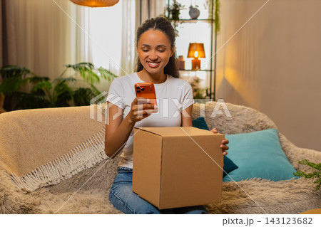 African American young woman on home sofa pleased after refund approval for defective delivery box African American young woman on home sofa pleased after refund approval for defective delivery box 143123682