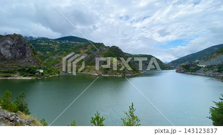 Coruh River opens through mountain valley, wide landscape view of green water, rocky slopes and rural homes in Turkey 143123837