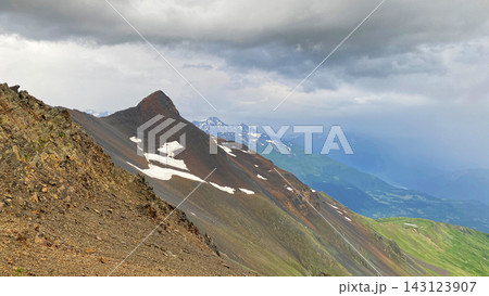 Snow patches tracing ridges in wide view across Svaneti, Georgia, where exposed rock layers and green slopes Snow patches tracing ridges in wide view across Svaneti, Georgia, where exposed rock layers and green slopes 143123907