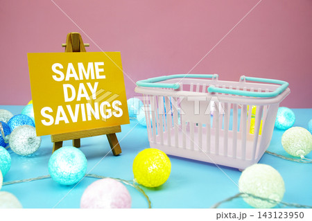 Same Day Savings text with shopping basket on blue background Same Day Savings text with shopping basket on blue background 143123950