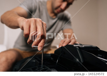 Selective focus shot of contractor male assembling new office chair, using allen key to tighten screws, building furniture for home or professional use, focusing on diy assembly and installation. Selective focus shot of contractor male assembling new office chair, using allen key to tighten screws, building furniture for home or professional use, focusing on diy assembly and installation. 143124572