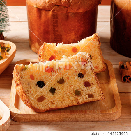 Sliced traditional Christmas panettone featuring a soft texture, candied fruit, and raisins, set on a table decorated for a festive celebration. Sliced traditional Christmas panettone featuring a soft texture, candied fruit, and raisins, set on a table decorated for a festive celebration. 143125993