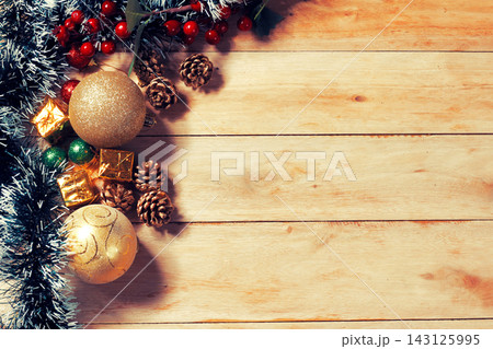 Christmas background on a rustic wooden table with gold ornaments, pine cones, red berries, and festive decor, with space for text. 143125995