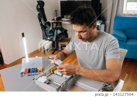 Concentrated technician or engineer working on switchboard installation. Hands on with tools and components, showing skill and precision in a modern workspace. DIY project or professional job. 143127504