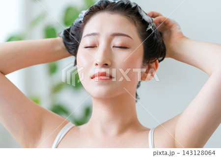泡立てたシャンプーで髪と頭皮をケアする女性 泡立てたシャンプーで髪と頭皮をケアする女性 143128064