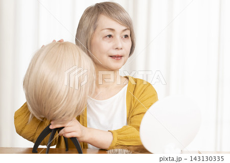 薄毛に悩みウイッグをつけるシニア女性 薄毛に悩みウイッグをつけるシニア女性 143130335