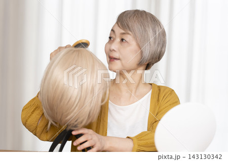 薄毛に悩みウイッグをつけるシニア女性 薄毛に悩みウイッグをつけるシニア女性 143130342