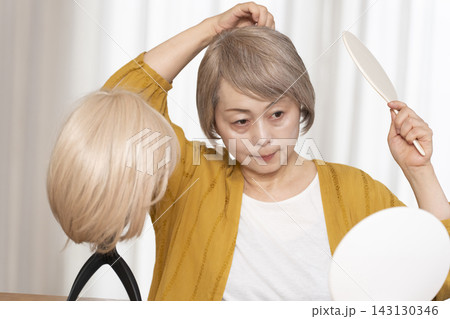 薄毛に悩みウイッグをつけるシニア女性 143130346