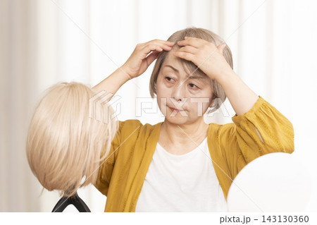 薄毛に悩みウイッグをつけるシニア女性 薄毛に悩みウイッグをつけるシニア女性 143130360