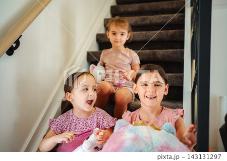 Three young girls playing with toys on stairs Three young girls playing with toys on stairs 143131297