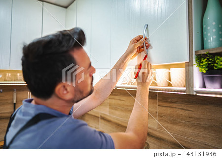 Handyman installing new kitchen cabinet handle in modern home 143131936