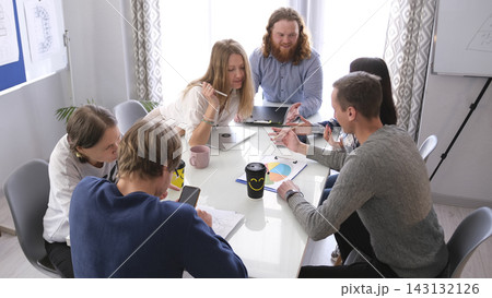 A group of people are sitting at a table and working on a project together. An atmosphere of cooperation and concentration 143132126